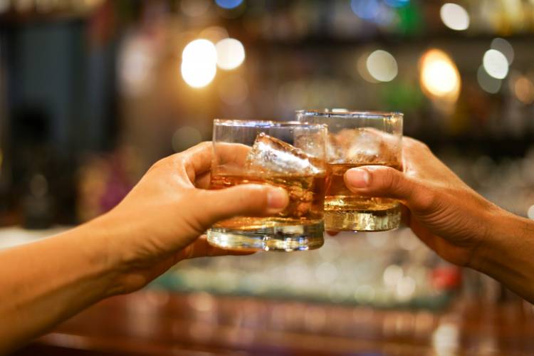 two people cheersing with a glass of whiskey