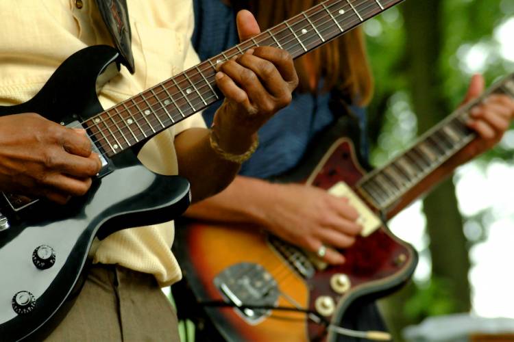 two people playing guitar with focus on the guitars