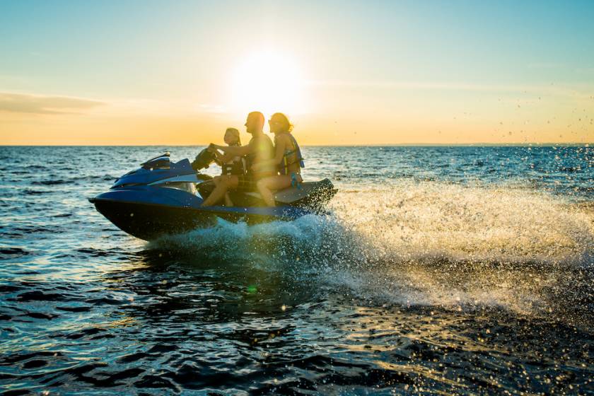 3 people on a jet ski at sunset